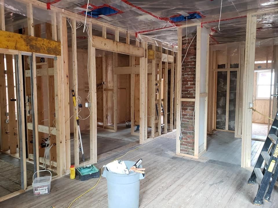 Exposed interior framing beside a brick chimney during construction.